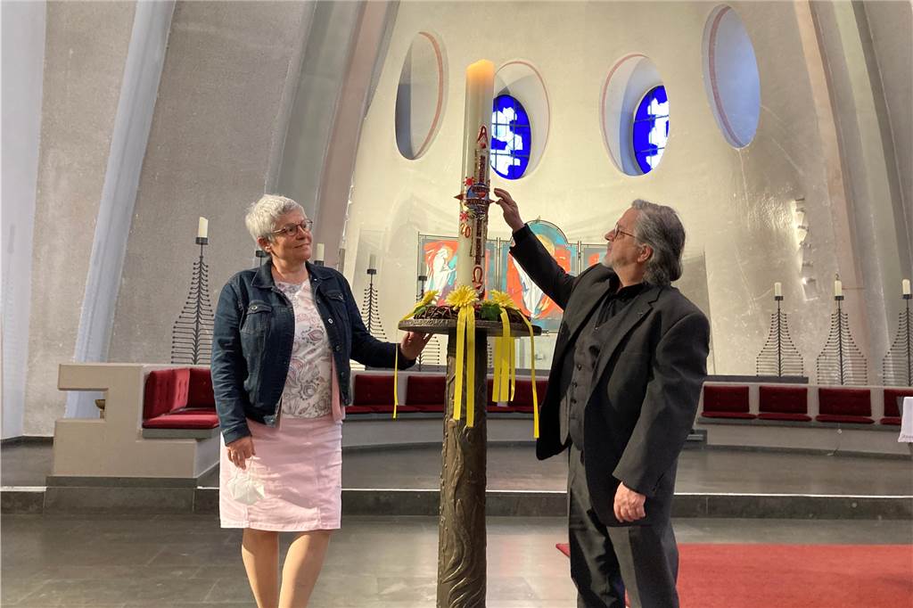 Castrop-Rauxels Impfkirche eröffnet: Über 260 Impfungen am ersten Tag Gudula Schumann aus dem Kirchenvorstand und Pastor Bernhard Dlugosch vor der Osterkerze in der St. Antonius Kirche. Auf der Kerze sind stilisierte Corona-Viren abgebildet, daneben steht: "Vater unser erlöse und von dem Bösen".