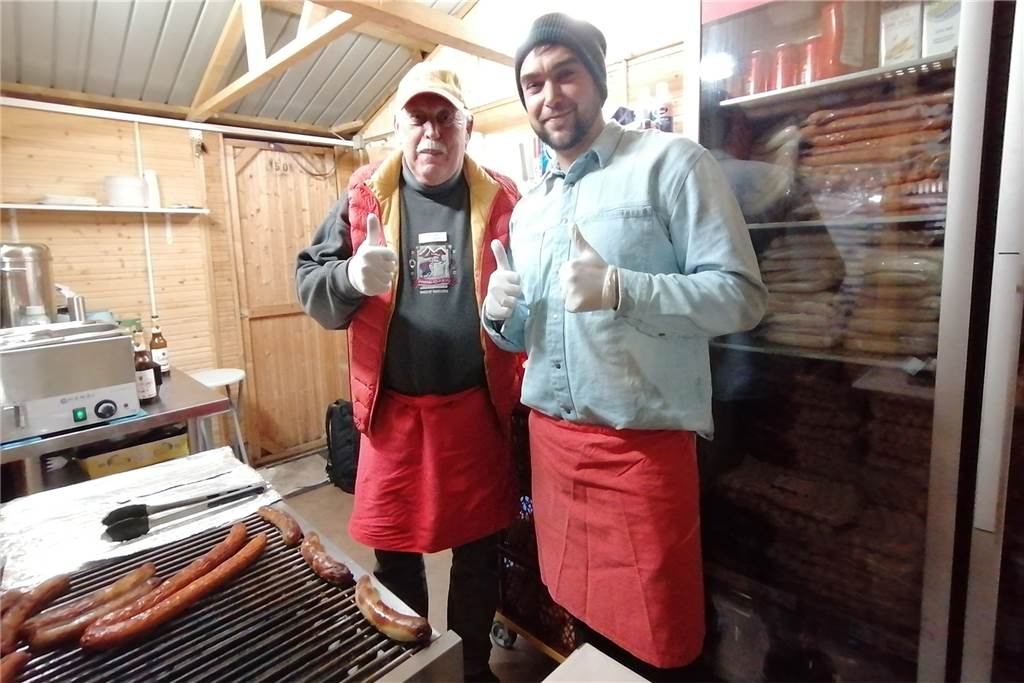 Zwei Mitarbeiter von Scheidings Lagerverkauf in einer Holzbude am Grill.