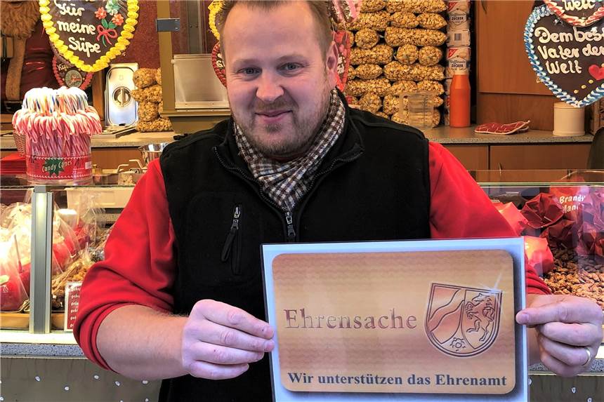 Ehrenamtskarte kommt auch auf dem Weihnachtsmarkt zum Einsatz Händler André Brandt zeigt das Schild, das die Stände markiert, an denen Inhaber einer Ehrenamtskarte Vergünstigungen bekommen.