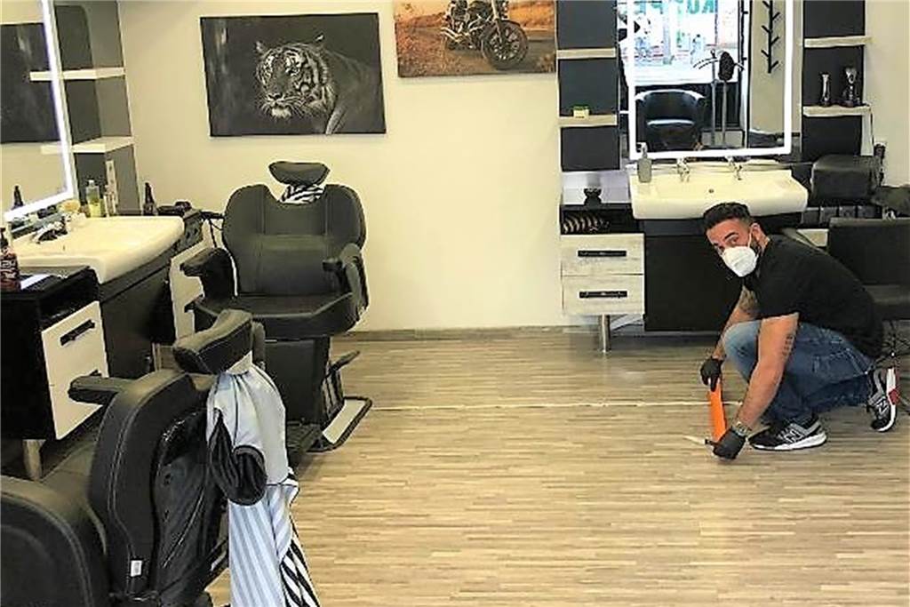 Hunderte Anfragen und Preiserhöhungen - Frisöre nach der Corona-Auszeit Hair-Brothers-Inhaber Erhan Karavin bereitet seinen Salon für die Wiedereröffnung vor. Hier richtet er gerade die Markierungen und Absperrungen ein.