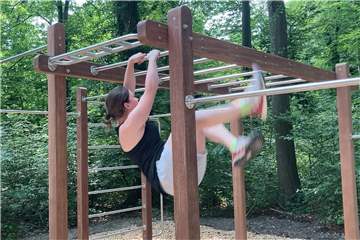 Hannah Wolf demonstriert bei der Eröffnung, wie die Sportgeräte des Calesthenics-Parcours im Volkspark Schwansbell genutzt werden können. Als Freiraumplanerin der Stadt Lünen hat sie auch bei der Umgestaltung entscheidend mit angepackt.