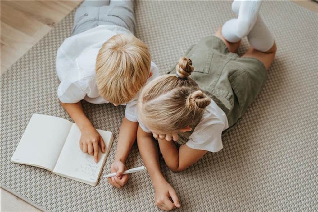 Tipps für den Schulstart: Gemeinsam den neuen Lebensabschnitt gestalten zwei kinder lesen und schreiben auf einem teppich