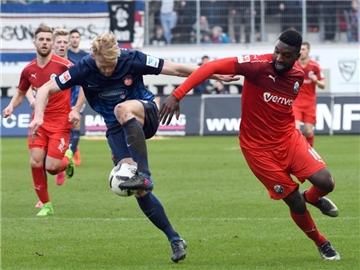 Heidenheims Sebastian Griesbeck (M) und Richard Sukuta-Pasu vom SV Sandhausen im Zweikampf. Foto: Stefan Puchner