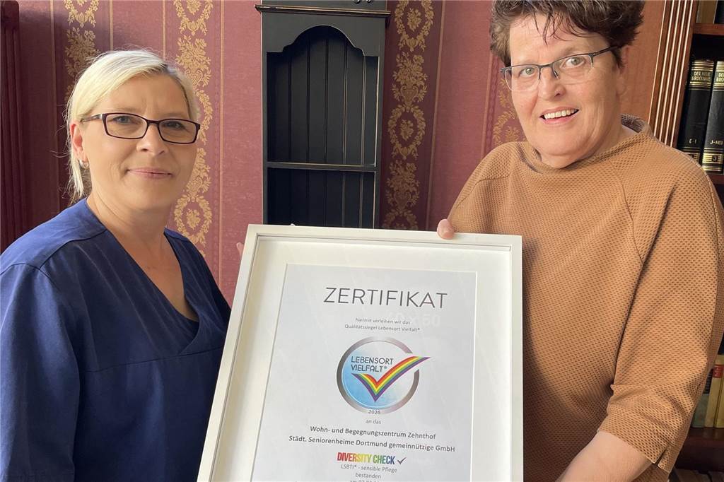 Anke Gerhardt fühlt sich für eine neue Liebe zu beeinträchtigt Zwei Frauen halten einen Bilderrahmen in die Höhe. Ein Regenbogen ist darauf zu sehen.