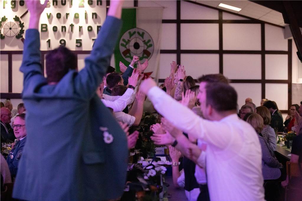 Eine Gruppe Menschen im Festzelt steht auf und jubelt mit erhobenen Armen.