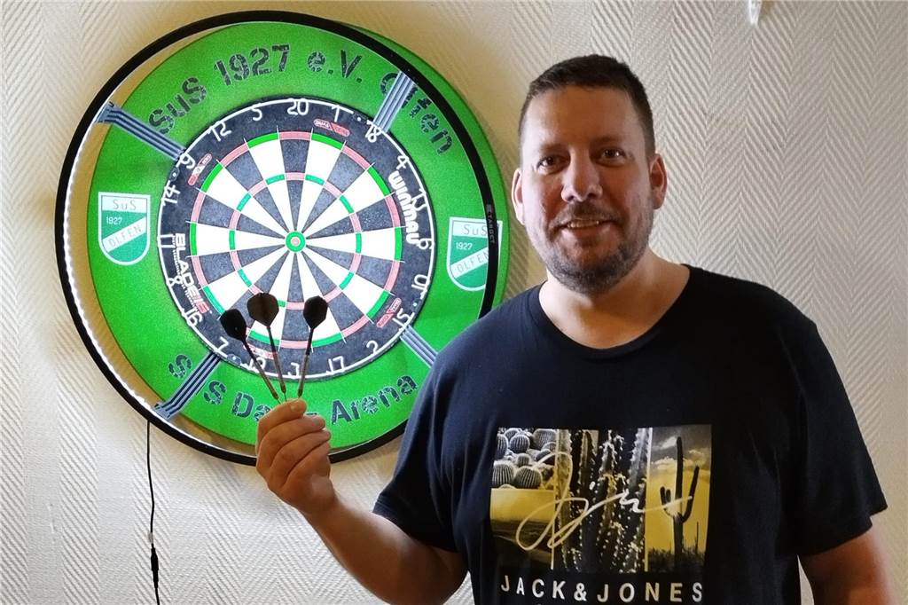 Der SuS Olfen hat mit Darts ein neues Sportangebot Hendrik Mollen steht vor einer Dartscheibe und hält drei Pfeile in die Hand.