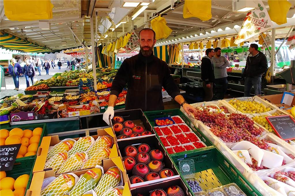 Markthändler Herr Temiz steht an seinem Obst- und Gemüsestand.