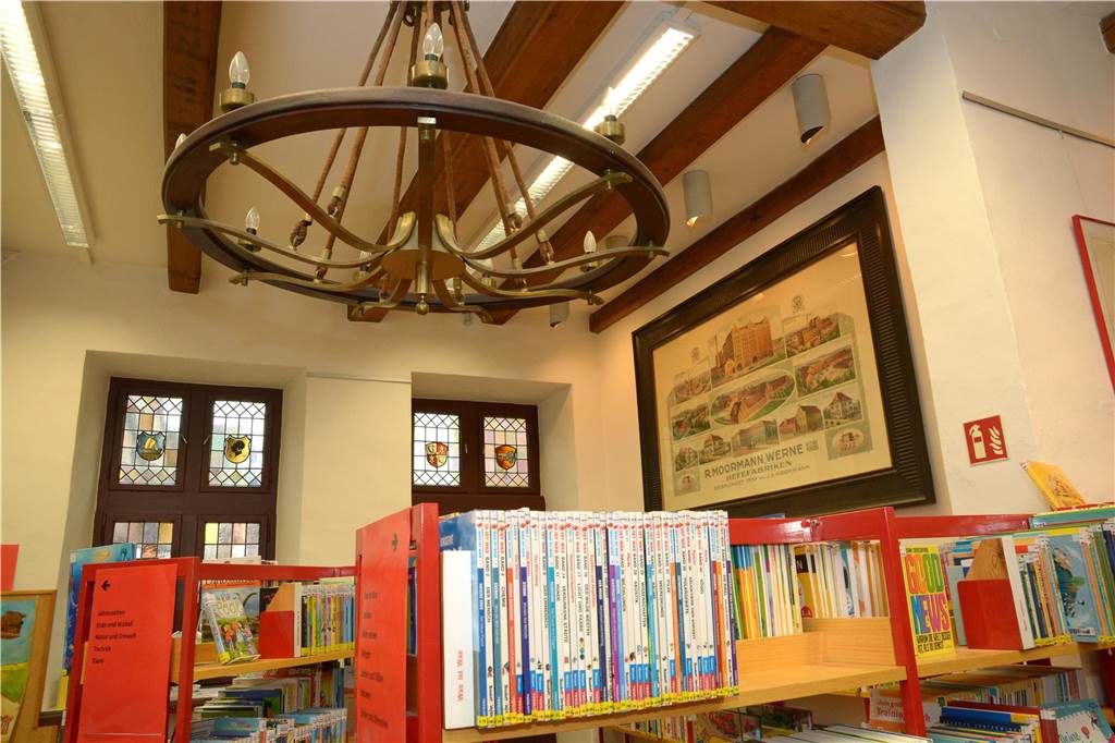 Hinter dem Bücherregal hängt eine alte Lampe