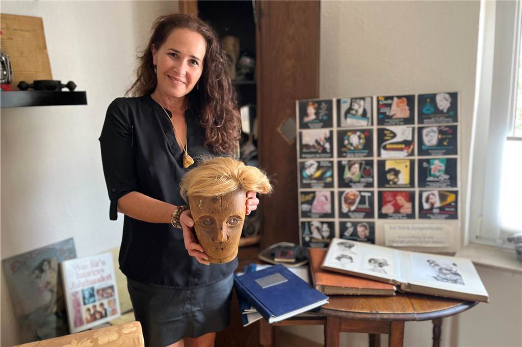 Nina Pawlowski schneidet Haare im Salon in ihrem ehemaligen Wohnzimmer Hölzerner Beistelltisch, Fotomappen mit Bildern von Großvater, Vater und Mutter und mehr: Nina Pawlowski hat vor etwa einem Jahr einen Friseursalon im Erdgeschoss ihres Wohnhauses eingerichtet. In ihrer Hand hält sie einen Holzkopf, den ein Toupet ziert. Das musste sie damals für ihre Meisterprüfung anfertigen.