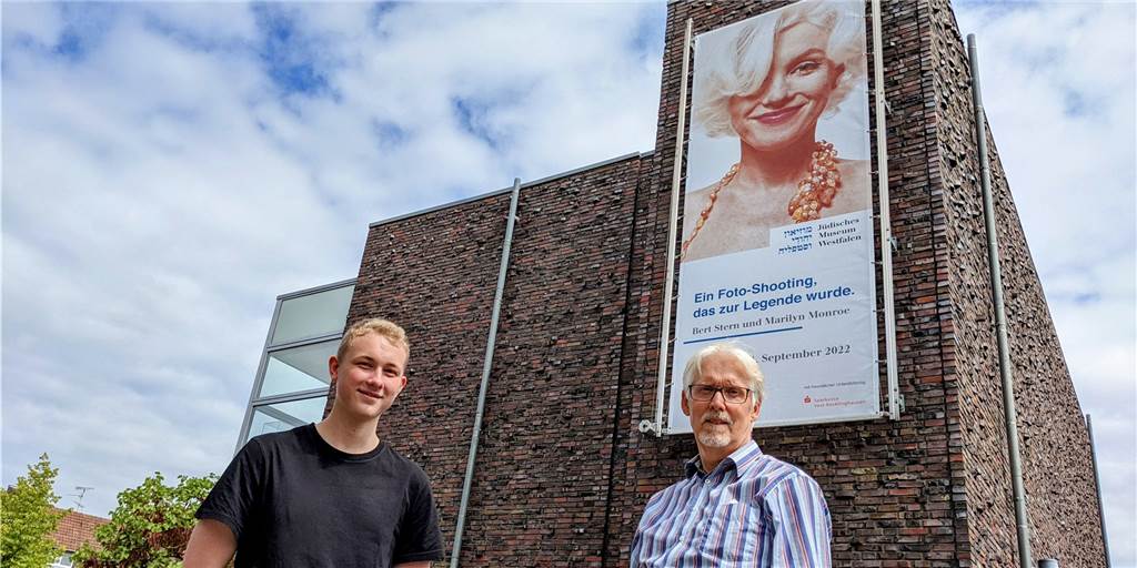 Menschen vor Plakatwand.