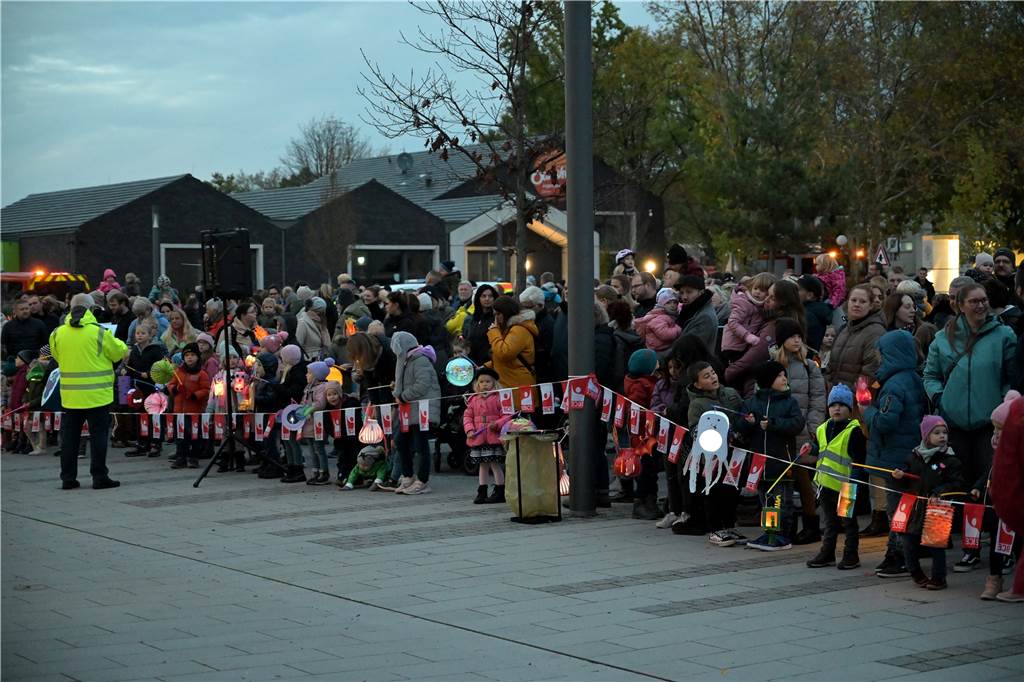 Kinder mit Laternen stehen am Straßenrand. 