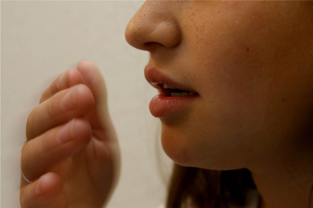 Grippewelle: „Die Infektionen sind heftiger und dauern länger“ Eine junge Frau hält sich die Hand vor den Mund.