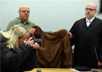 Ihr Anwalt (r.) und ein Anwaltsgehilfe verdeckten die Angeklagte vor Gericht mit einer Jacke.