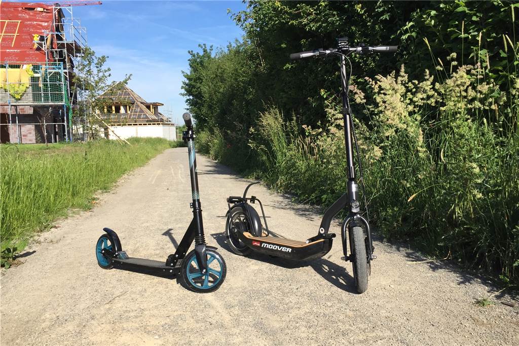 Pendeln mit dem E-Scooter ist einfach, praktisch, noch haben die E-Roller aber einen Haken Im direkten Vergleich mit einem kleinen Tret-Scooter sieht man den Größenunterschied zum E-Scooter von Metz. Das wirkt sich auch aufs Gewicht aus: Der Moover ist deutlich schwerer, lässt sich aber trotzdem gut tragen.
