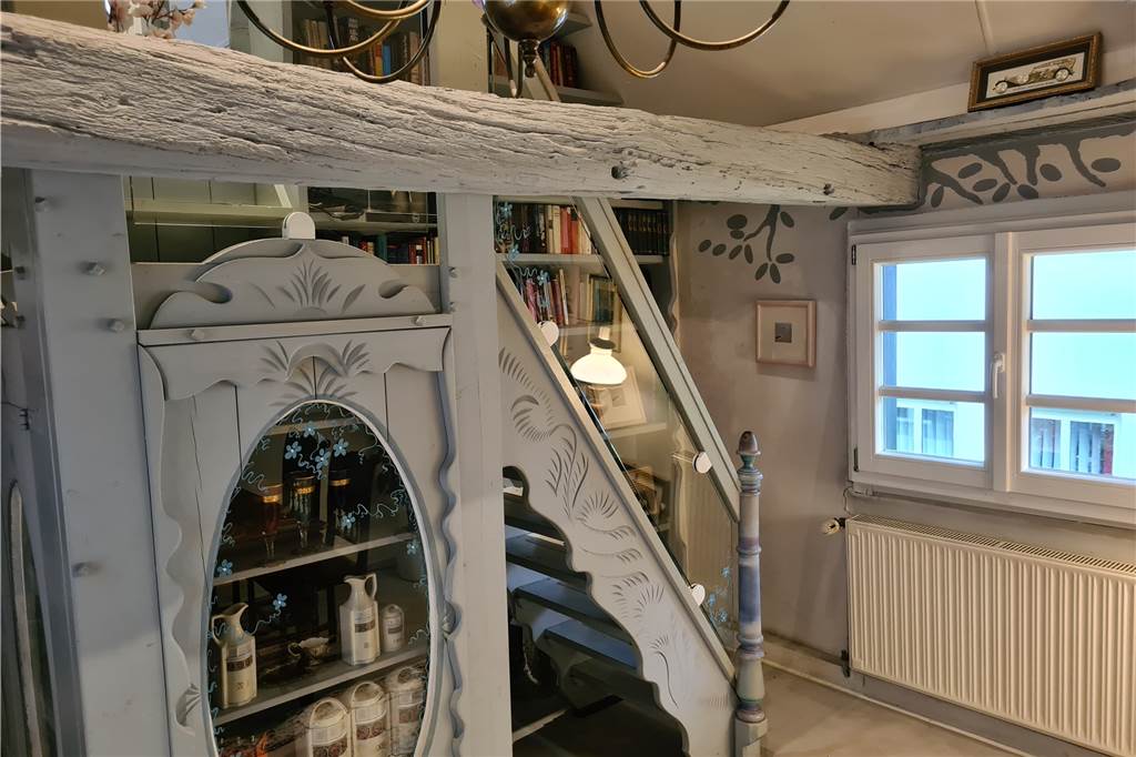 Im Inneren des Hauses führt eine verzierte Holztreppe auf die Etage unter dem Dach.