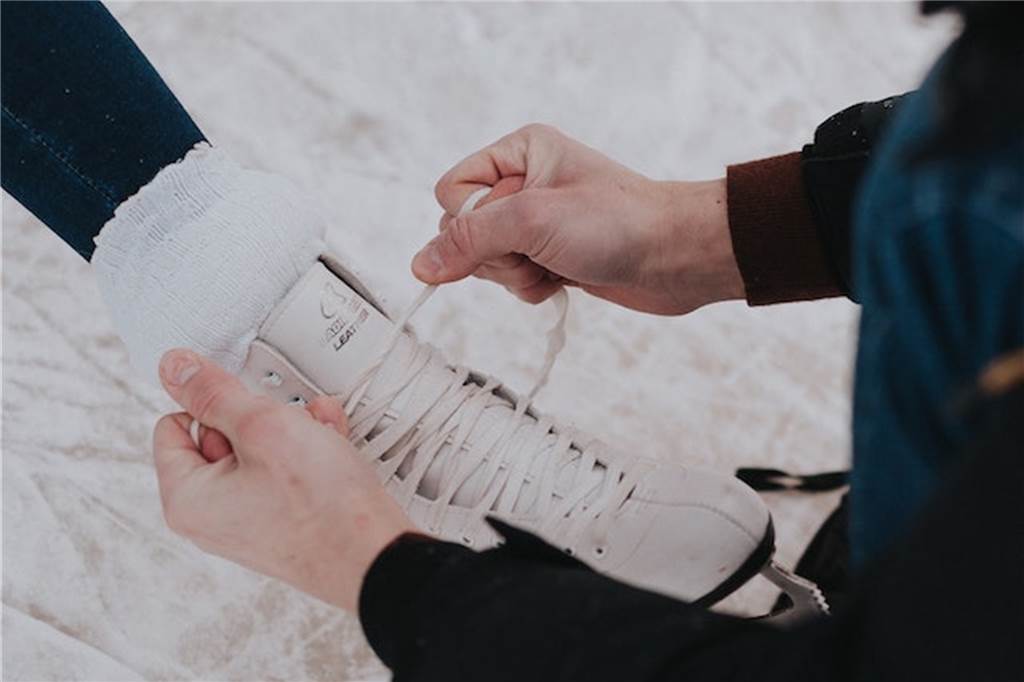 Heiß auf Eis? Die besten Schlittschuhbahnen im Winter 2022/23 ein schlittschuh der gerade von jemand anderem geschnürt wird