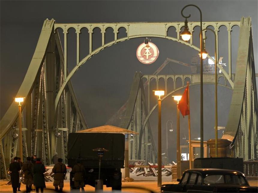 Gedenken an Mauerbau vor 54 Jahren Im vergangenen Jahr wurde die Glienicker Brücke mit dem Wappen der DDR geschmückt - für Dreharbeiten von Regisseur Steven Spielberg. Einen Tag nach dem Mauerfall 1989 wurde die Brücke zwischen West-Berlin und Brandenburg geöffnet. Foto: Ralf Hirschberger/Archiv