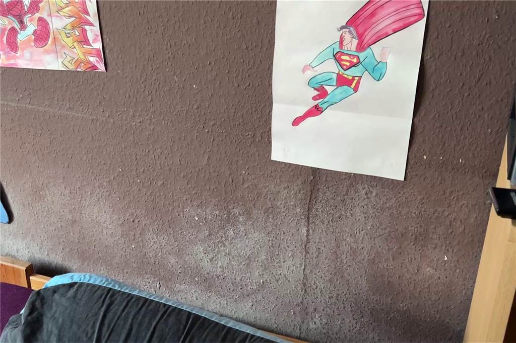 Verzweifelte Mutter: Angst nach dem Brand und Schimmel an den Wänden Schimmel an der Wand, darüber ein Superman-Bild.