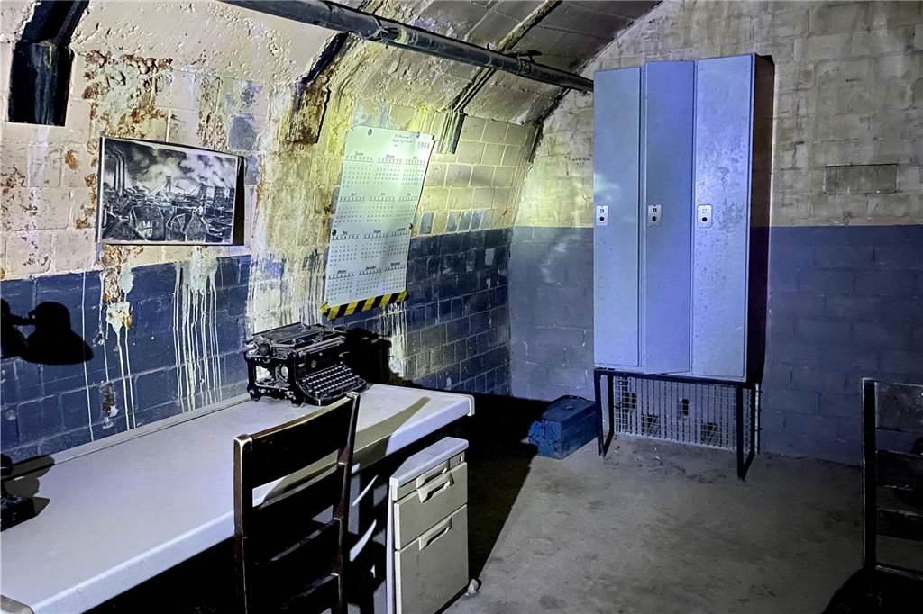 Dritter Escape-Room geplant: Im Trainingsbergwerk knifflige Rätsel lösen Ein heruntergekommener Raum im Trainingsbergwerk Recklinghausen mit beschmierten Wänden, möbliert mit einem Schreibtisch, einem Stuhl, einem Spind und einer alten Schreibmaschine.