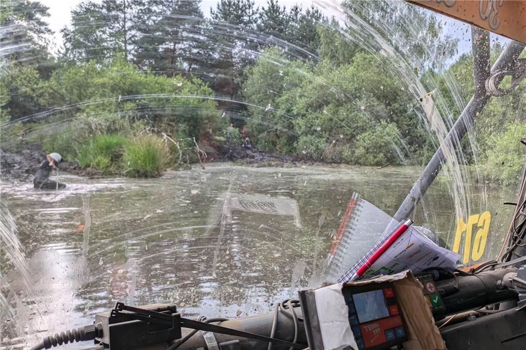 Mit dem Unimog Alfred Wemhoff und Team fahren durch Wasser und Schlamm Blick auf ein Gewässer.