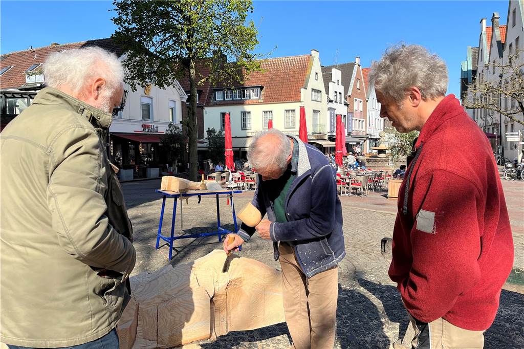 Besucher schauen dem Künstler bei der Arbeit zu.