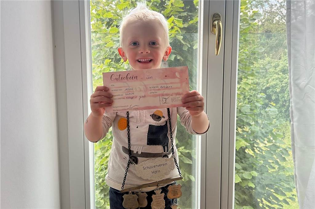 Dreijähriger Kinderschützenkönig: Julius ist bislang Jüngster in Horn Ein Junge hält einen Gutschein vor sich und lächelt. Dabei trägt er eine silberne Kette.