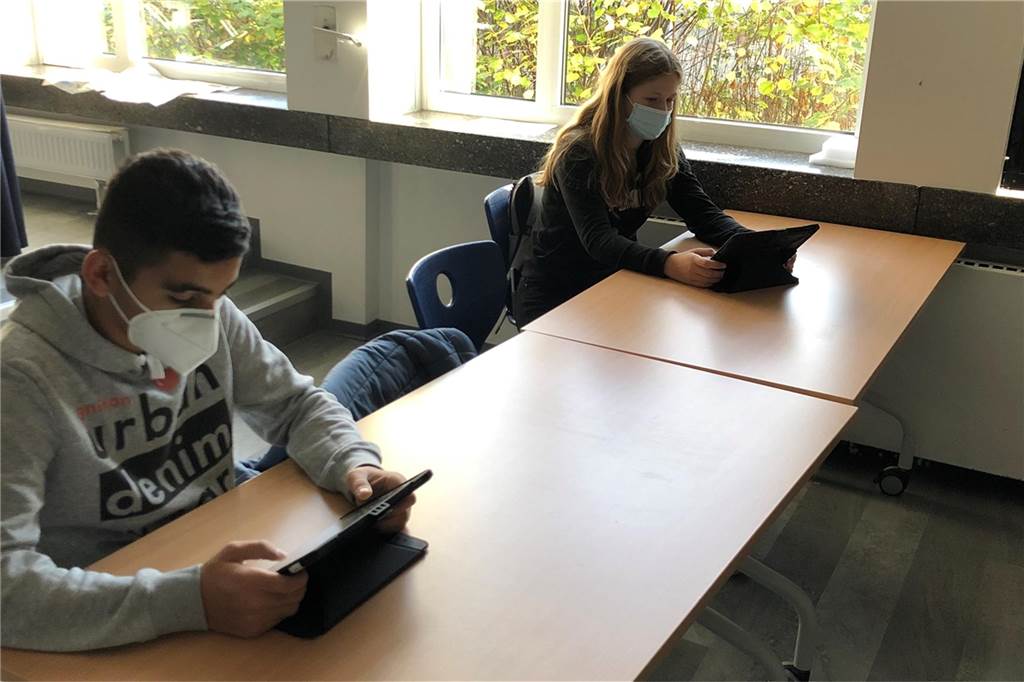 Über 600 I-Pads mehr bis 2025: Stadt investiert in digitale Schulen Schüler sitzen mit einem ipad und Maske während der Pandemie am Tisch.