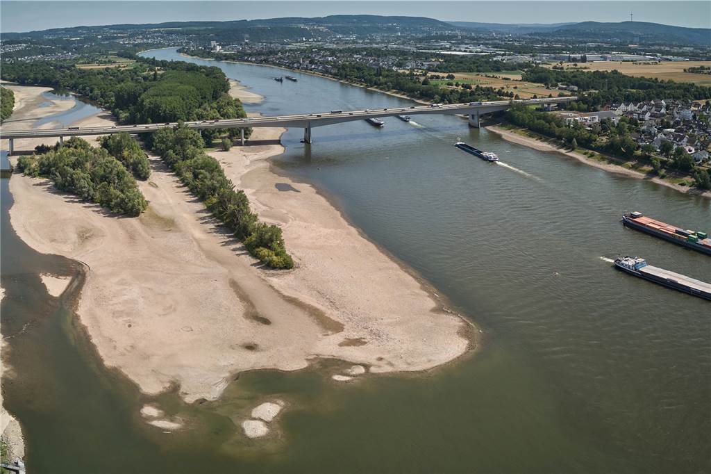 Es ist viel zu trocken: „Faktisch haben wir bereits eine Wasserkrise“ Frachtschiffe passieren bei Bendorf am Rhein eine Sandbank (Luftaufnahme mit einer Drohne).