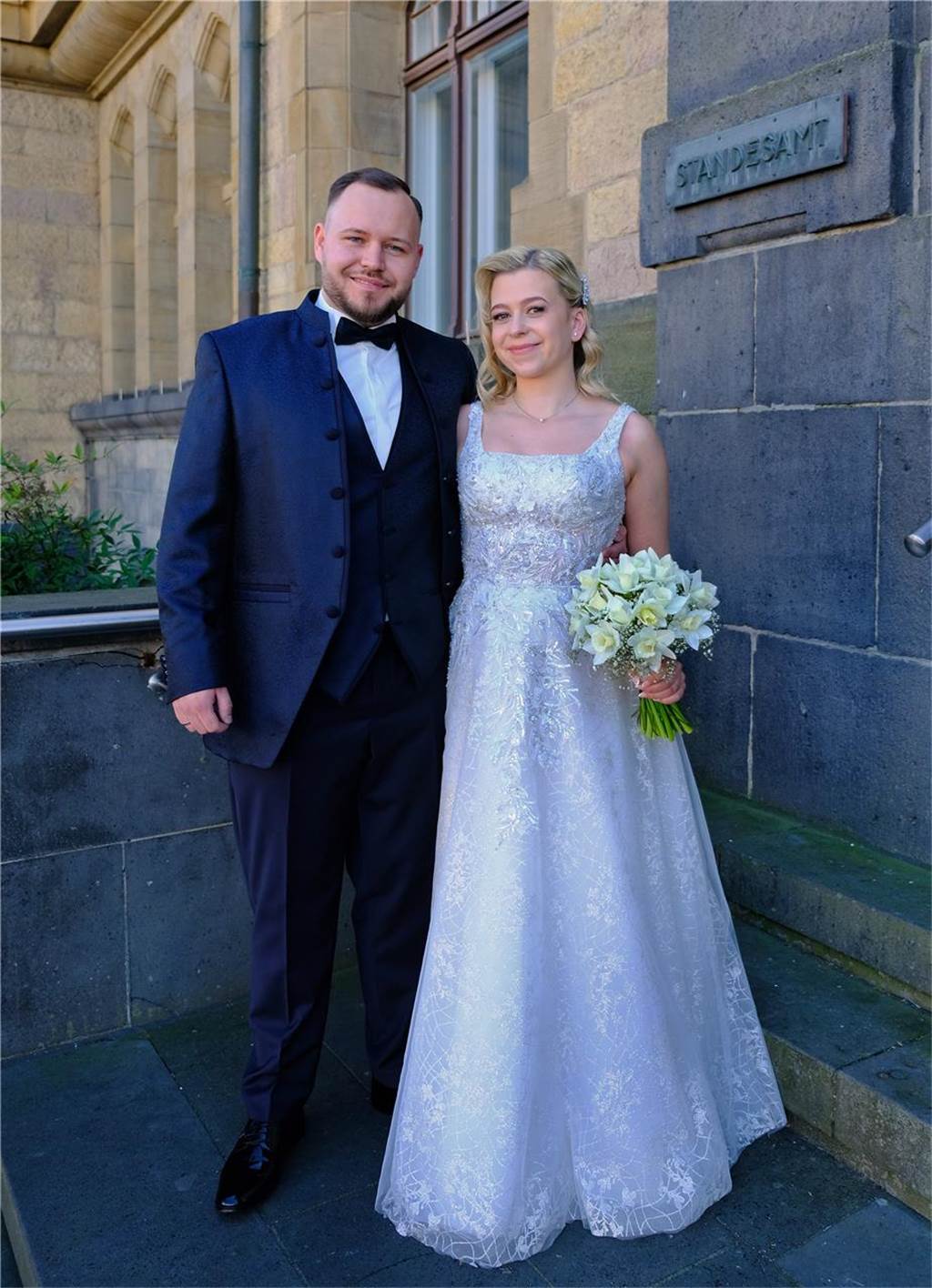 Das frisch vermählte Ehepaar Bianca Magiela und Lennart Munka steht in Brautkleid und Anzug vor dem Rathaus Recklinghausen.
