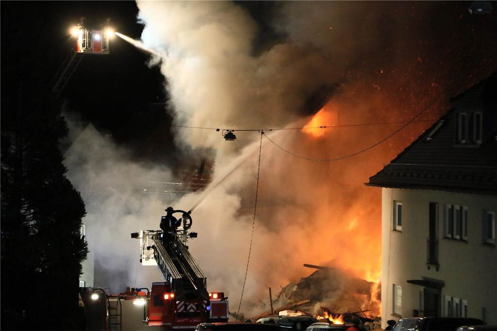 Wohnhaus in Stuttgart nach Explosion teils eingestürzt: Feuerwehr geht von Gasexplosion aus Feuerwehrleute auf Drehleitern löschen ein Wohnhaus.