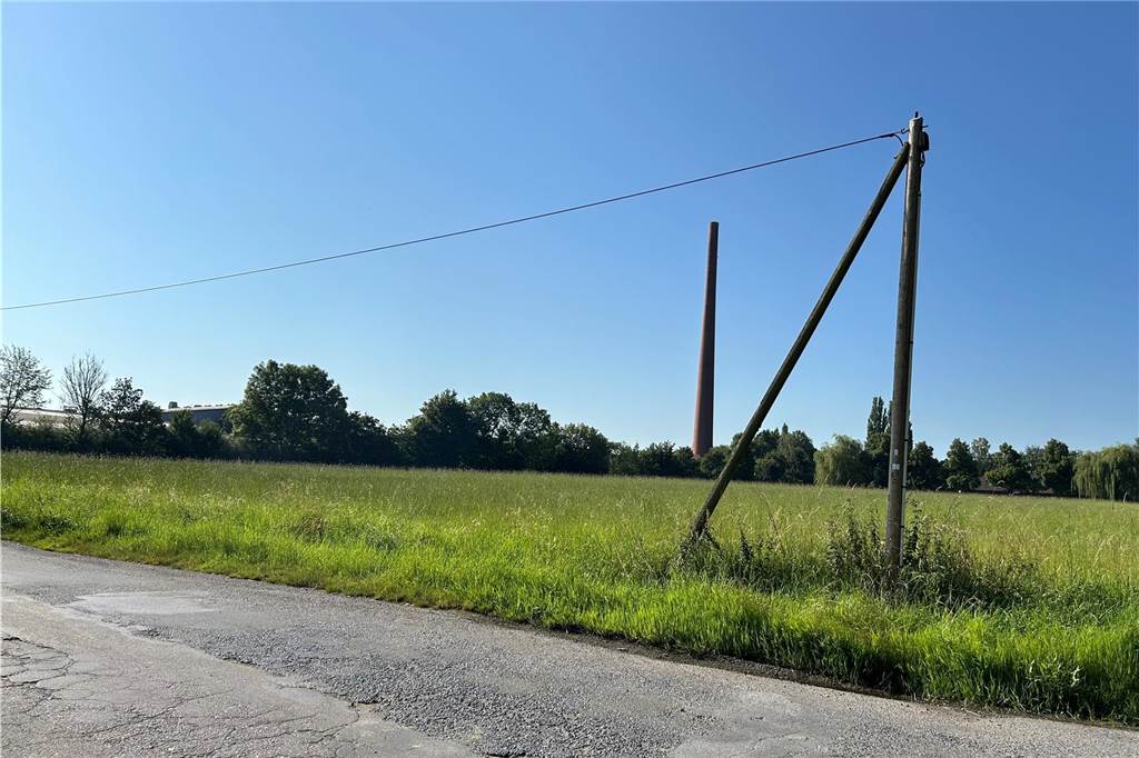 Wiese mit hohem Schornstein im Hintergrund