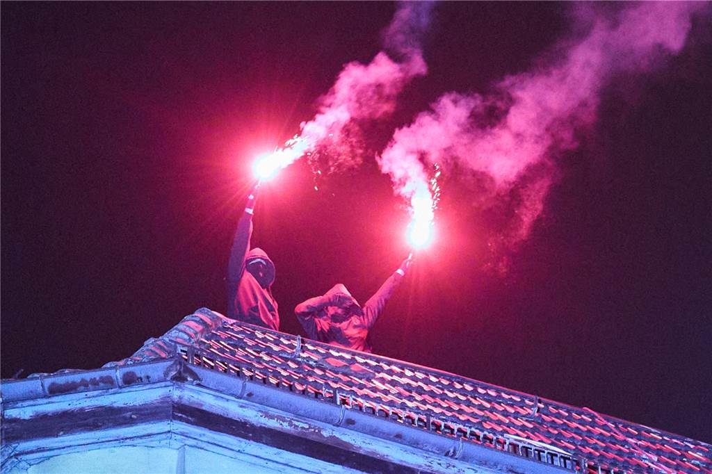 Menschen zünden Pyrotechnik von einem Haus.
