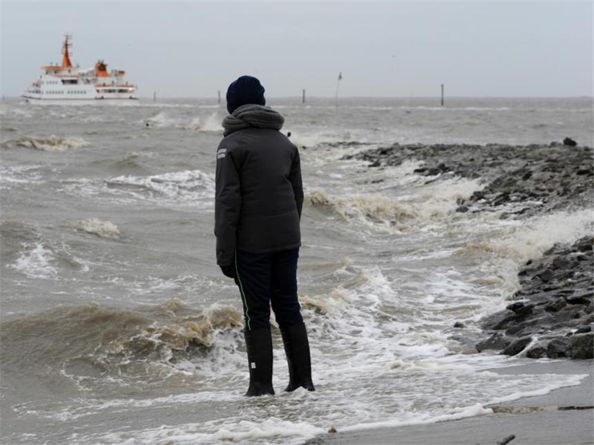 Meteorologen warnen vor Orkan und Hochwasser In der sturmgepeitschten Nordsee stehend, schaut ein Junge einem auslaufenden Seebäderschiff hinterher. Foto: Ingo Wagner/Archiv