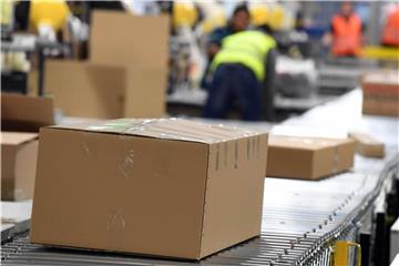 In einem Amazon Logistikzentrum laufen Pakete auf einem Band zum Versand. Foto: Uli Deck/Illustration