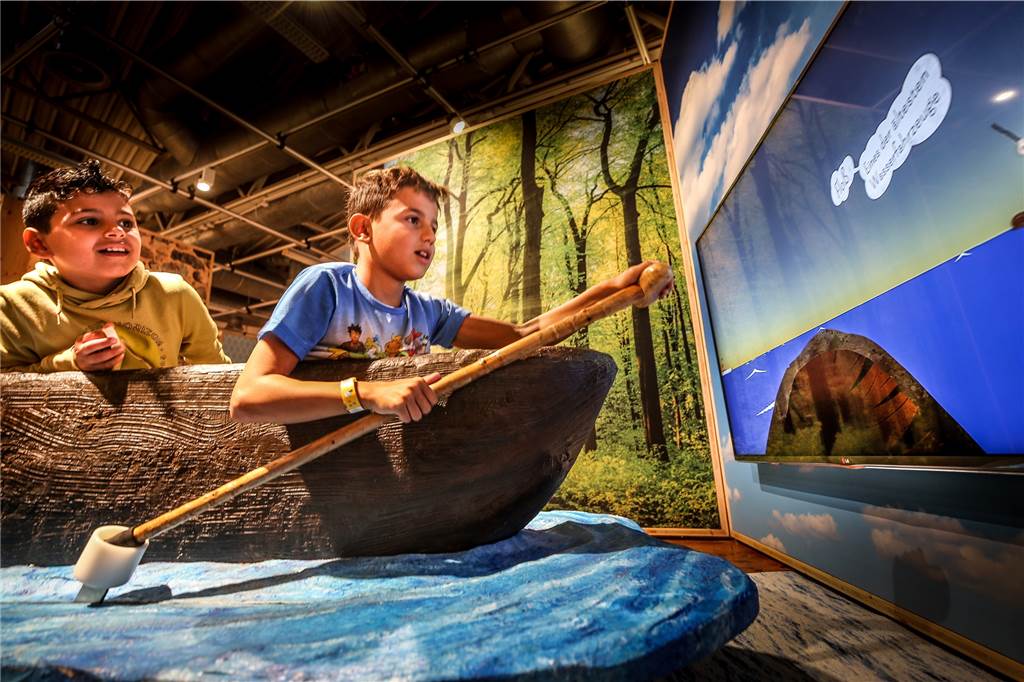 Neue Mitmach-Ausstellung für kleine Tüftler startet in der DASA In einem Boot können die Schüler paddelnd etwas über die Geschichte des Ruderns lernen. Die Ruderbewegungen werden auf den Bildschirm vor ihnen übertragen.