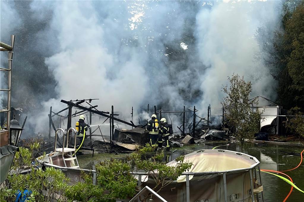 Nach heftigem Brand mit Explosionen: Nagetier für Feuer verantwortlich Feuerwehrleute löschen einen Gartenlaubenbrand.