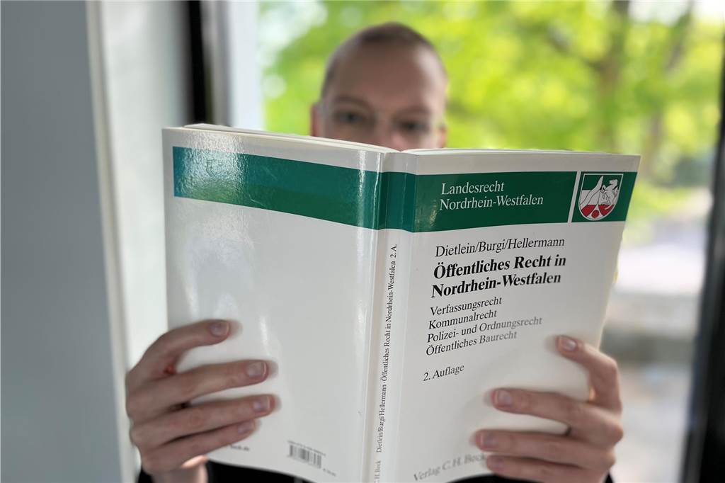 Eine Frau in einem Büro in Unna schaut in ein Lehrbuch über das Öffentliche Recht in Nordrhein-Westfalen.