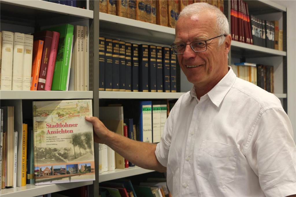 Ulrich Söbbing entwickelte aus trockenen Akten lebendige Geschichte Archivar steht vor einem Regal und zeigt ein Buch