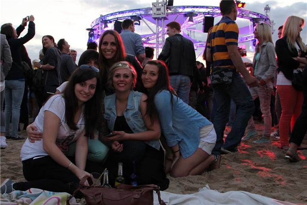 Das erste Sunset Beach Festival: Schlecht-Wetter-Prognosen und Mücken Fünf Frauen sitzen zusammen auf dem Sandstrand vor der Bühne.
