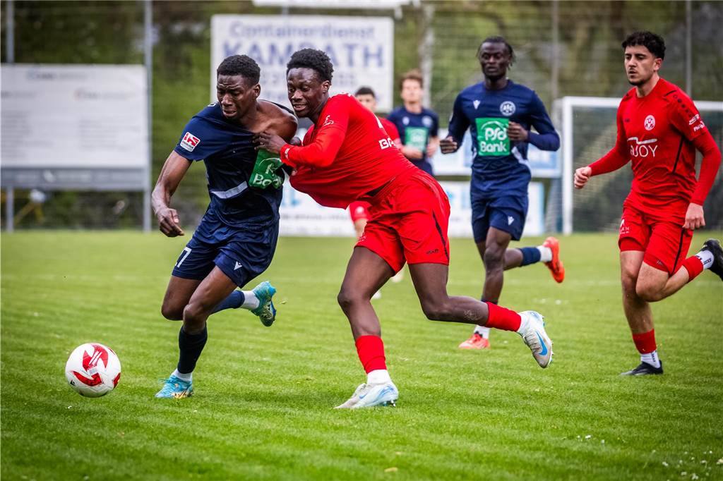 Ein intensiver Zweikampf, bei dem ein Fußballer am Trikot des anderen zerrt.