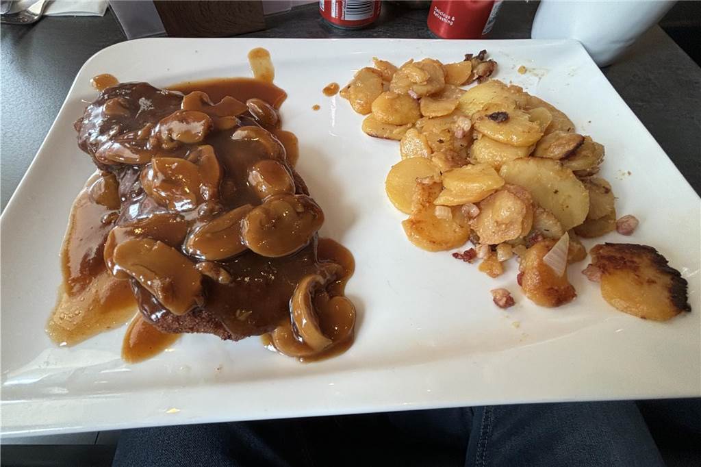 Wurscht Factory eröffnet – Hohe Qualität zu kleinen Preisen Jägerschnitzel mit Bratkartoffeln auf einem quadratischen weißen Teller.
