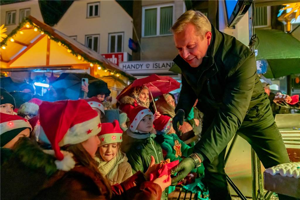 Lünens Bürgermeister Jürgen Kleine-Frauns verteilt Stücke des Lebkuchenherzens.