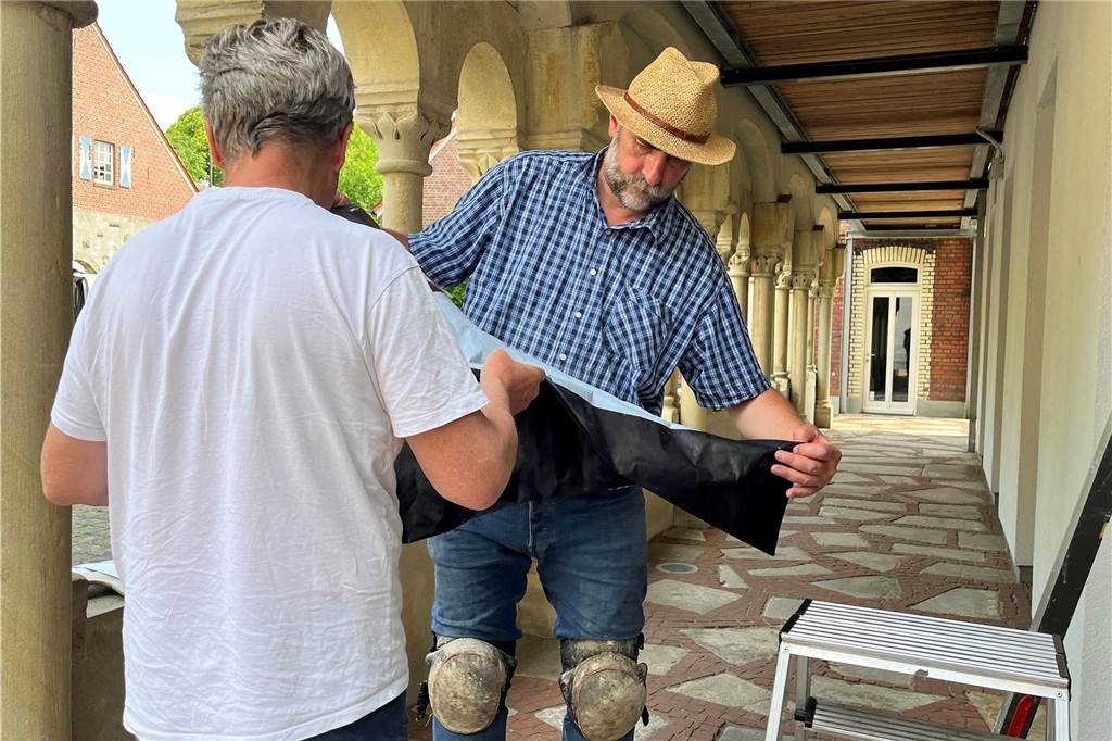 David Mannstein und Steffen Mittelsdorf falten ein Stück Foto-Kollage auseinander.