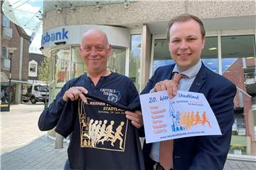 Dirk Böhle und Philipp Gärtner zeigen T-Shirt und Plakat für den Volksbank-Stadtlauf in Werne.