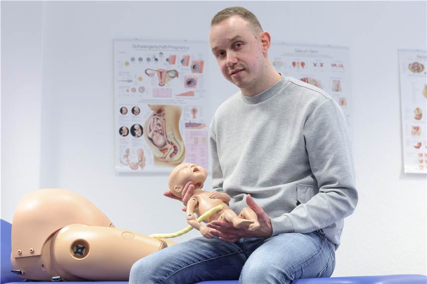 Als Mann im Frauen-Beruf Hebamme - im Kreißsaal eine extreme Ausnahme Jonas Küppers, männliche Hebamme, hält eine Neugeborenen-Übungspuppe mit Nabelschnur. Küppers absolviert ein duales Studium, um den Beruf der Hebamme zu lernen.