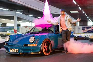 JP Kraemer vor einem blauen Sportwagen und Feuerwerk