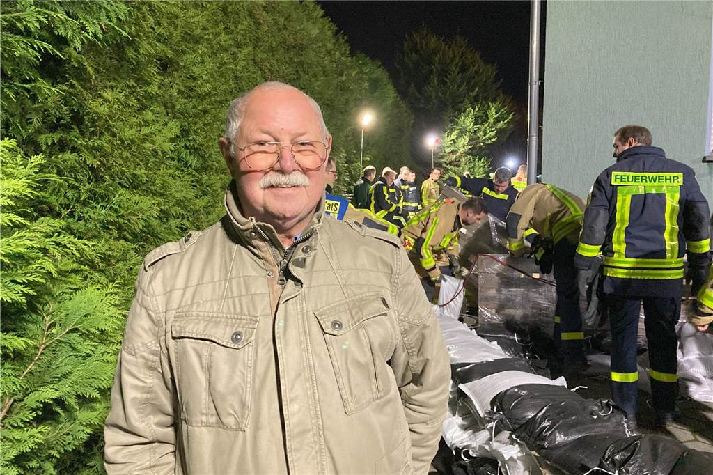Pegel an Borker Straße sinkt: Von Entwarnung kann nicht die Rede sein Jürgen Exner steht neben seinem Haus in Waltrop. Im Hintergrund schichten Leute von Feuerwehr und THW einen Wall aus Sandsäcken auf.