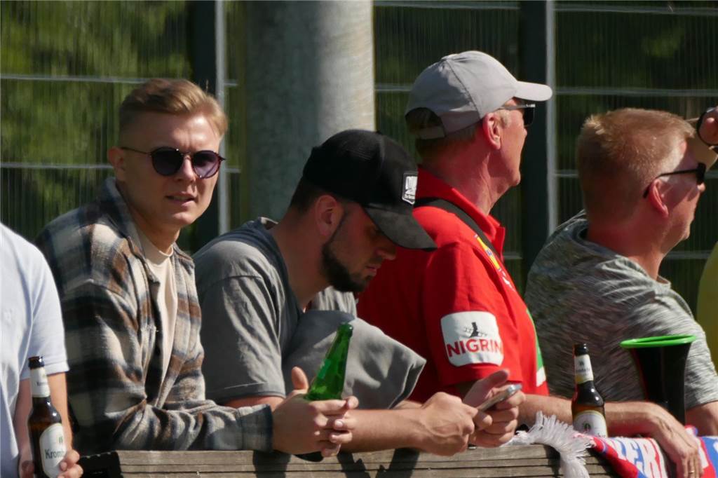 Julian Siegel im Karohemd, Sonnenbrille und Sprite-Flasche hinter der Bande vom Werner SC.