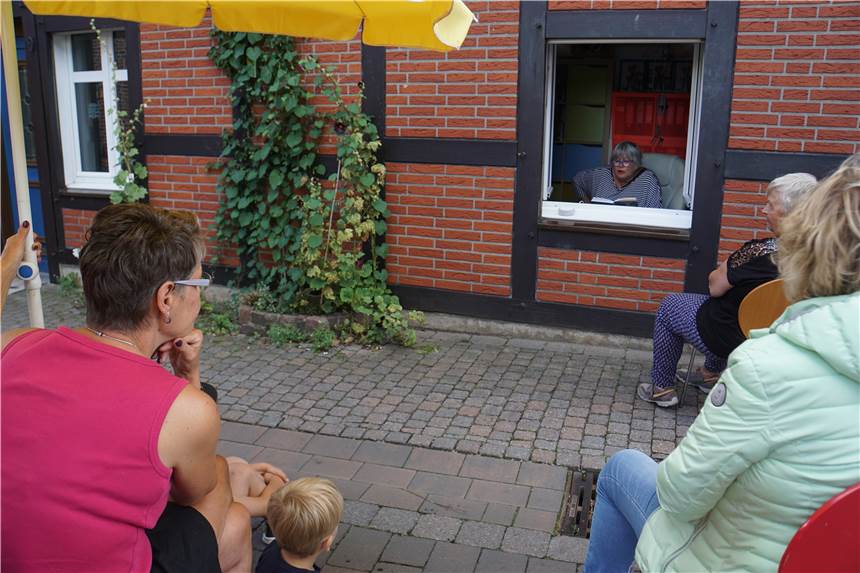 Am Bolzplatz, Friedhof oder Fischstand: „Eine Gemeinde liest“ in Herbern startet Jutta Richter liest wie hier 2020 wieder aus ihrem Fenster heraus. An vielen besonderen Orten findet „Eine Gemeinde liest“ wieder in der Gemeinde Ascheberg statt.