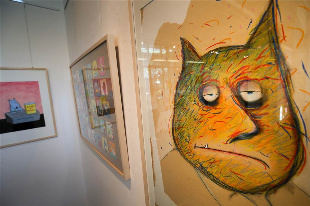 Cartoonist Ari Plikat zieht mit „Kunst macht Rücken“ ins Depot Katzen sind oft ein wiederkehrendes Motiv bei Ari Plikat. Im Hintergrund ist die Bierdeckelsammlung im Rahmen erkennbar.
